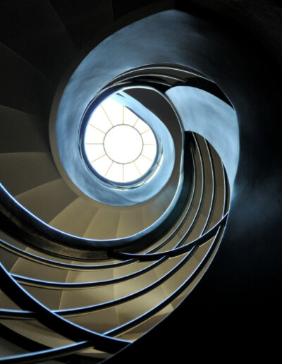 creative image of the inside spiral of a dark staircase with a ceiling window in the centre